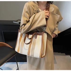Detail view of large canvas tote bag showing brown leather handles and adjustable shoulder strap