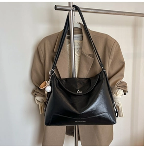 Close-up of black matte leather tote with metal lock and baseball glove charm detail