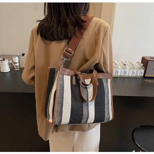 Vertical striped canvas tote bag with brown leather trim and wide fabric shoulder strap