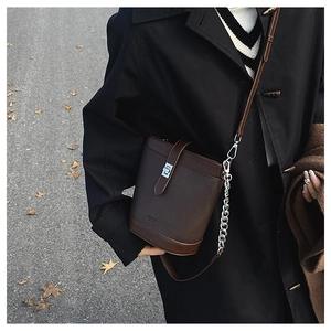 Detail of dark brown leather bucket bag featuring silver twist lock and chain strap