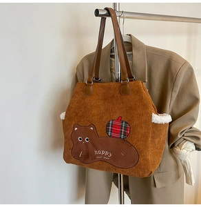 Detail of corduroy tote bag featuring animal embroidery and plush faux fur side pockets