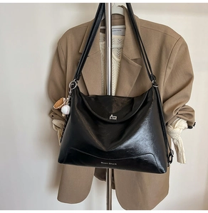 Detail of glossy black leather tote bag with silver twist lock and baseball bag charm