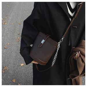 Detail of dark brown pebble leather bucket bag with silver hardware on an autumn street