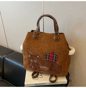 Close-up of brown corduroy tote bag with cat embroidery and white fleece edge details