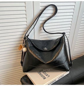 Detail of black leather tote bag with silver metal twist lock and unique baseball charm