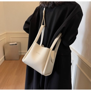 Close-up of cream leather bucket bag with pebble texture and thick handle strap
