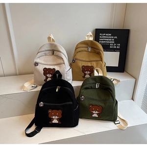 Detailed display of four corduroy mini backpacks in cream, yellow, black and green