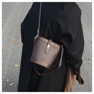 Detail of lychee pattern leather bucket bag with silver metal twist lock and logo