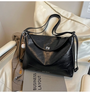 Detail of glossy black tote bag with silver metal twist lock and a baseball charm