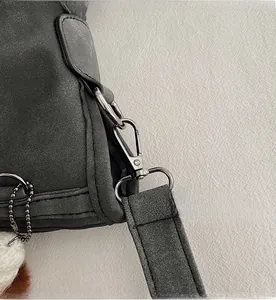 Detail of dark gray matte handbag featuring gun-metal hardware and plush charm accessory