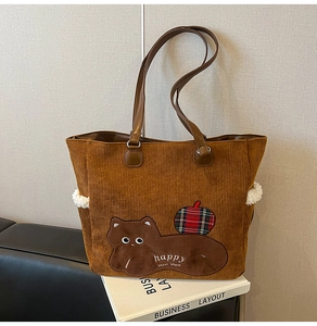 Detail of brown corduroy tote bag featuring cat patch embroidery and lamb wool trim texture