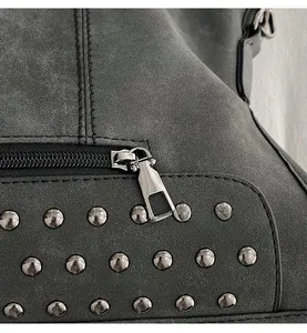 Detailed macro view of smooth silver zipper pull and metal rivets on charcoal faux leather