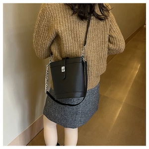 Close-up of black pebble leather bucket bag featuring silver turn-lock and chain strap