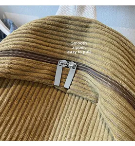 Detailed macro view of smooth double metal zippers on mustard corduroy backpack