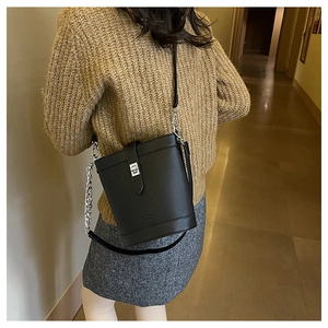 Detail of black lychee grain leather bucket bag with silver twist lock and slim shoulder strap