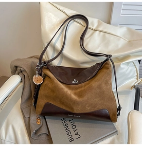 Close-up of brown suede tote bag featuring a leather strap and baseball glove charm detail