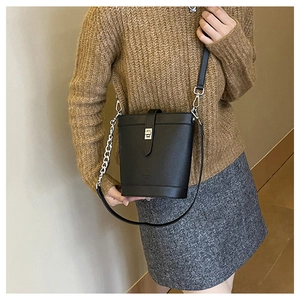 Side view of black textured leather bucket bag with silver lock and chain strap