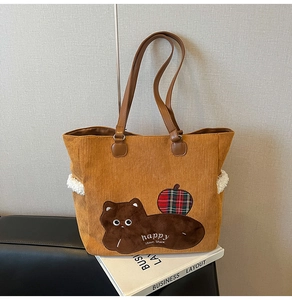 Detail of corduroy tote bag showing plush bear embroidery and textured fabric