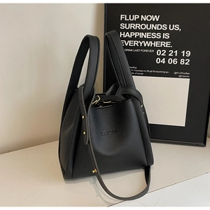 Close-up of black lychee grain leather bucket bag with gold hardware and embossed logo