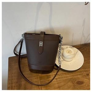 Detail of dark brown bucket bag featuring lychee grain texture and metal chain accent