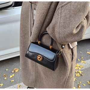 Detail of black glossy leather handbag featuring a vintage gold twist lock buckle