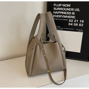 Detailed view of taupe lychee leather texture and gold stud strap on bucket bag