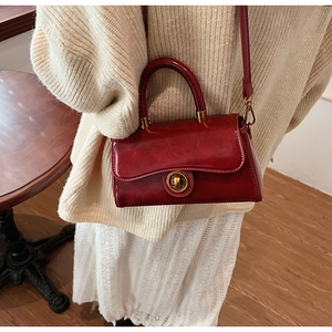 Detail showing vintage red crossbody bag with golden clasp and polished leather texture