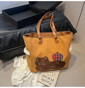 Detail of yellow corduroy tote bag featuring a cute cat patch and embroidered happy text