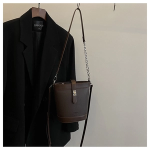 Detail of dark brown bucket bag with lychee texture and silver twist lock