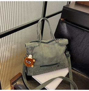 Detail of dark green tote bag with silver studs and cute fuzzy charm on textured seat
