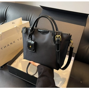 Detail of black oxford tote with leather handles, gold hardware, and detachable strap