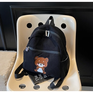 Detail of black corduroy backpack with cute bear embroidery on a modern chair