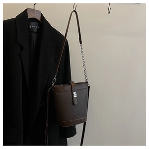 Detailed macro view of dark brown litchi pattern leather bucket bag with silver buckle