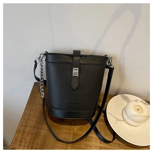 Detail of black bucket bag with pebble leather texture and silver twist lock closure