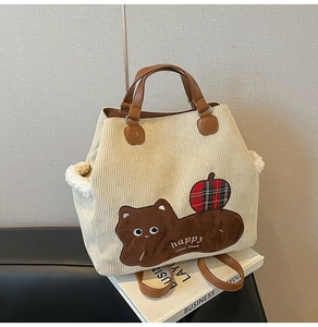 Detail of corduroy tote bag with cat patch, brown leather straps and fleece trim edges