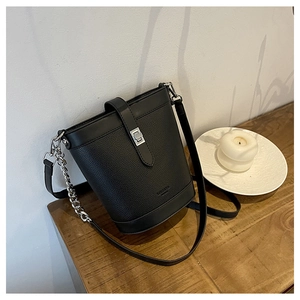 Detail of black pebbled leather bucket bag featuring silver twist lock and chain strap