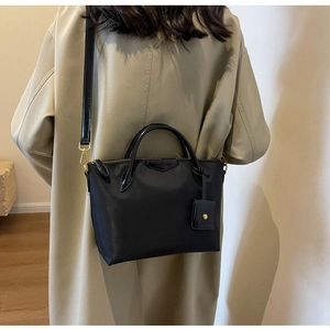 Detailed back view of a black Oxford cloth tote bag with leather straps and gold hardware