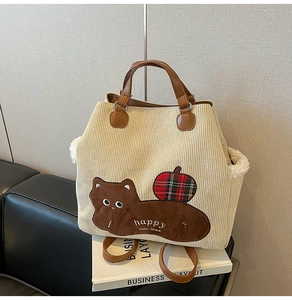 Detailed texture of beige corduroy tote with brown cat patch and faux shearling trim