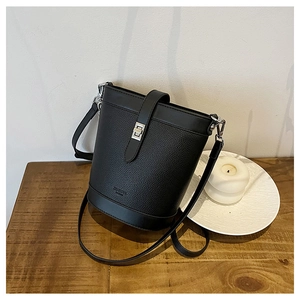 Detail of lychee pattern leather bucket bag with silver hardware on a wooden table