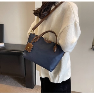 Detail of navy nylon tote bag with leather handles and removable small charm pouch