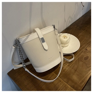 Close-up of white bucket bag with pebble leather texture and silver rotating metal lock