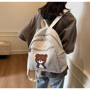 Detail of cream corduroy backpack back showing shoulder straps and bear embroidery