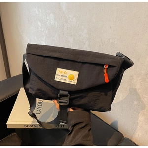 Detail der wasserdichten Nylon-Umhängetasche mit Smiley-Patch und orangefarbenem Reißverschluss