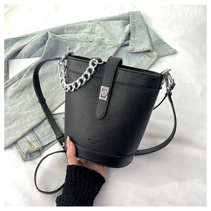 Close-up of black pebble leather bucket bag featuring silver chain and metal clasp detail