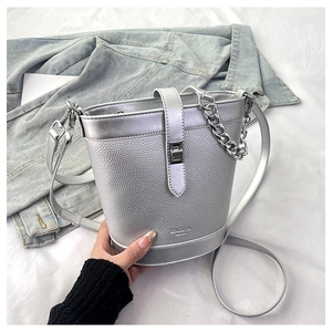 Macro view of silver bucket bag showing pebbled leather texture and metal chain strap