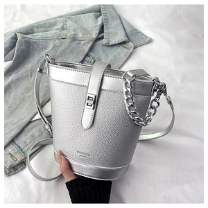 Detail of silver bucket bag with litchi texture, metal chain, and crossbody strap