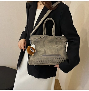 Detail view of vintage matte tote bag showing decorative studs and plush charm