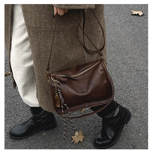 Détail du sac bandoulière en cuir marron vintage avec garniture dorée et étiquette