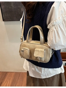 Cream multi-pocket bowling handbag with adjustable shoulder strap shown on model