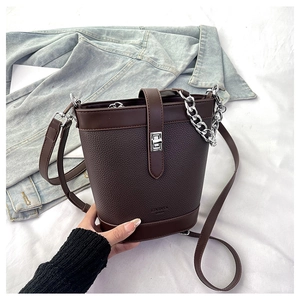 Detail of dark coffee bucket bag with lychee grain leather, silver lock and metal chain